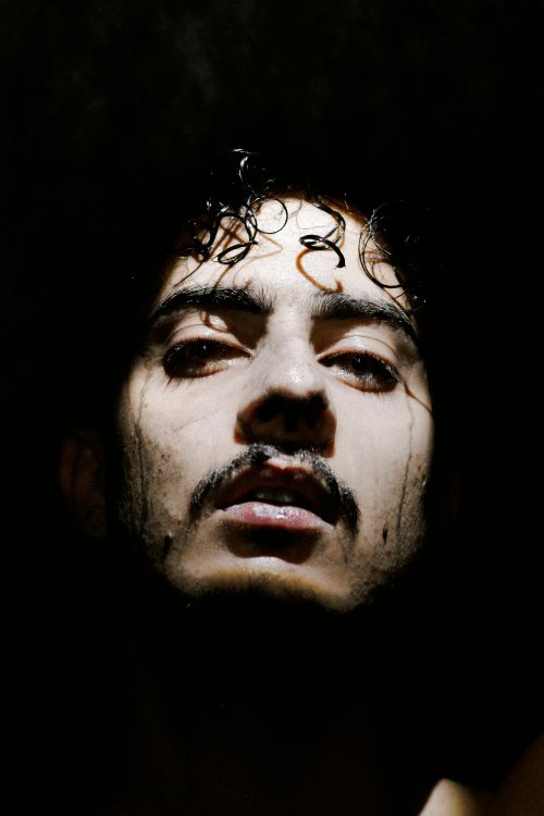 Free Intense artistic portrait of a man with wet hair and dramatic shadows. Stock Photo