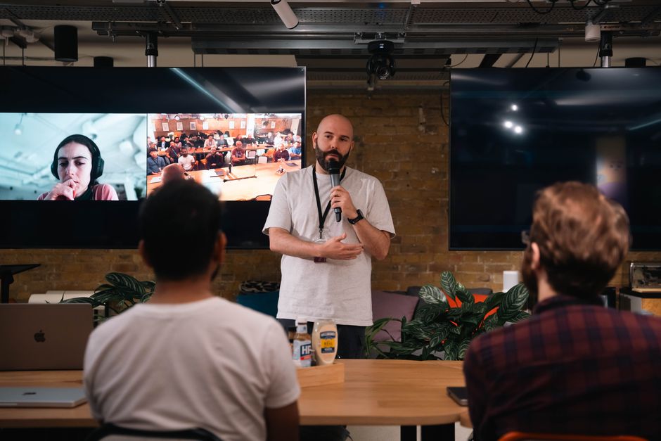 guide to virtual presentation skills - A speaker delivers a presentation at a tech conference with virtual attendees on screen.