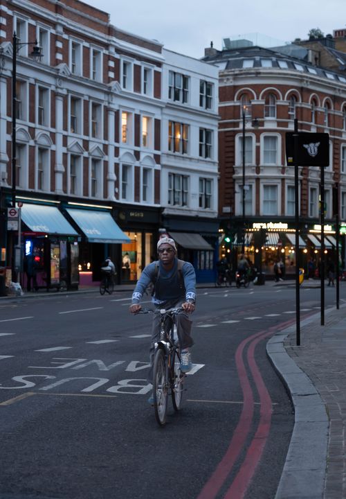 Free A cyclist riding on a city street surrounded by historic buildings at dusk, capturing urban life. Stock Photo