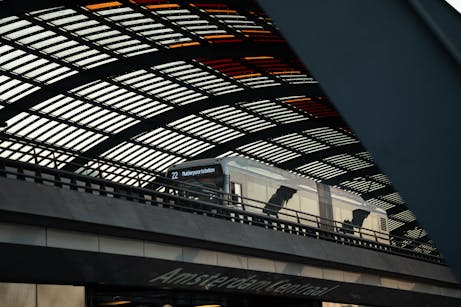 Train at Amsterdam Central Station under the modern, geometric roof structure.