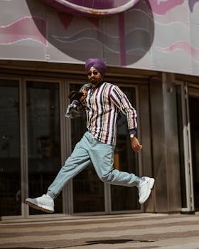 Fashionable man with turban jumping at Coney Island, showcasing street style and vibrant energy.