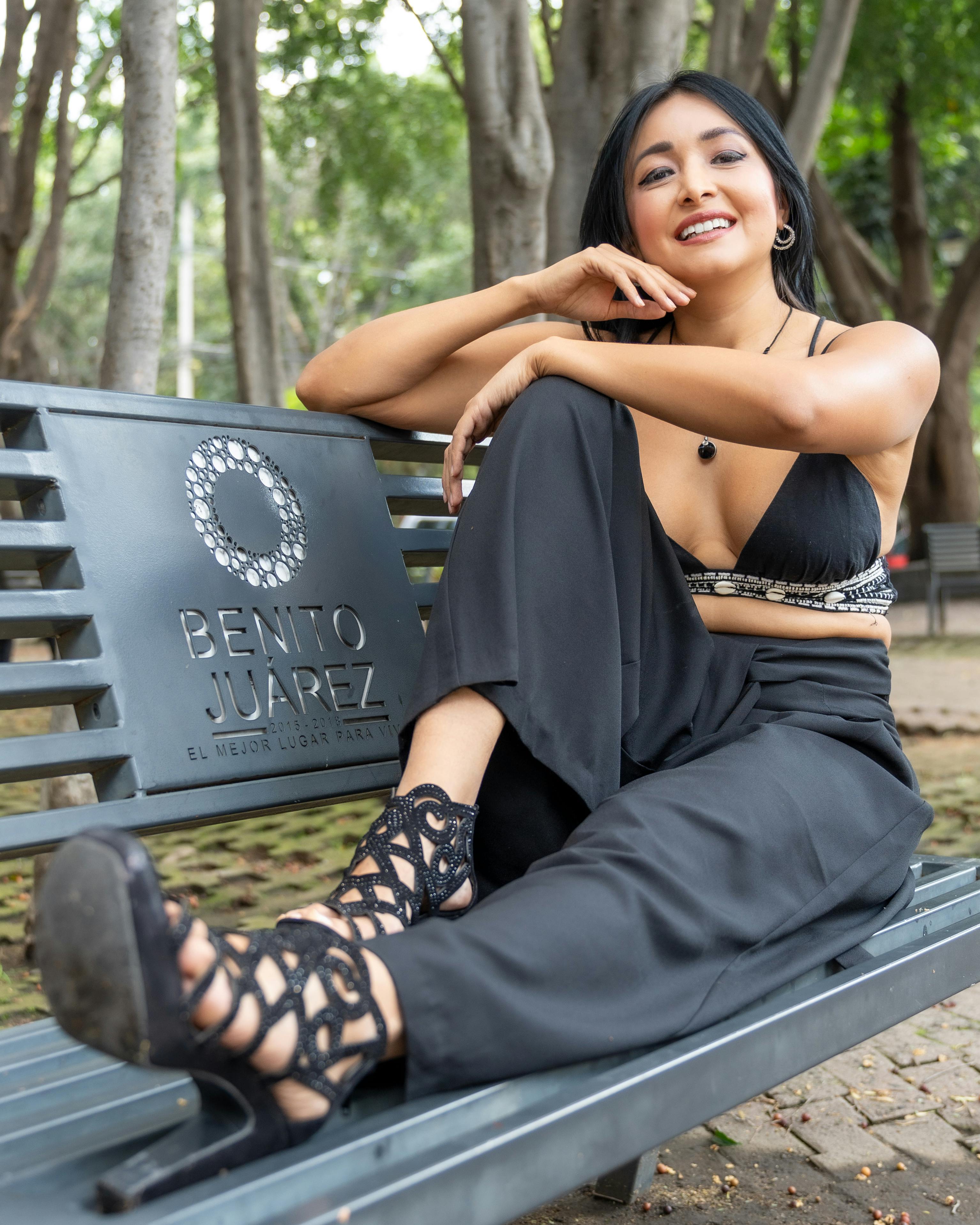 Beautiful woman in stylish attire relaxing on a bench in a Mexico City park. Vibrant and confident.