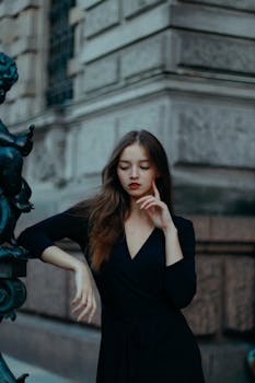 Stylish woman posing elegantly by urban architecture, showcasing modern fashion.