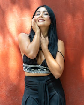Happy woman enjoying sunlight against a bright red wall in Mexico City.