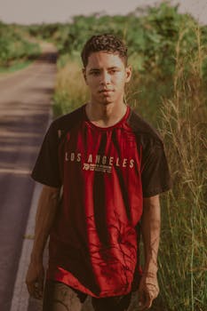 一名年轻人自信地站在绿树成荫的小路边