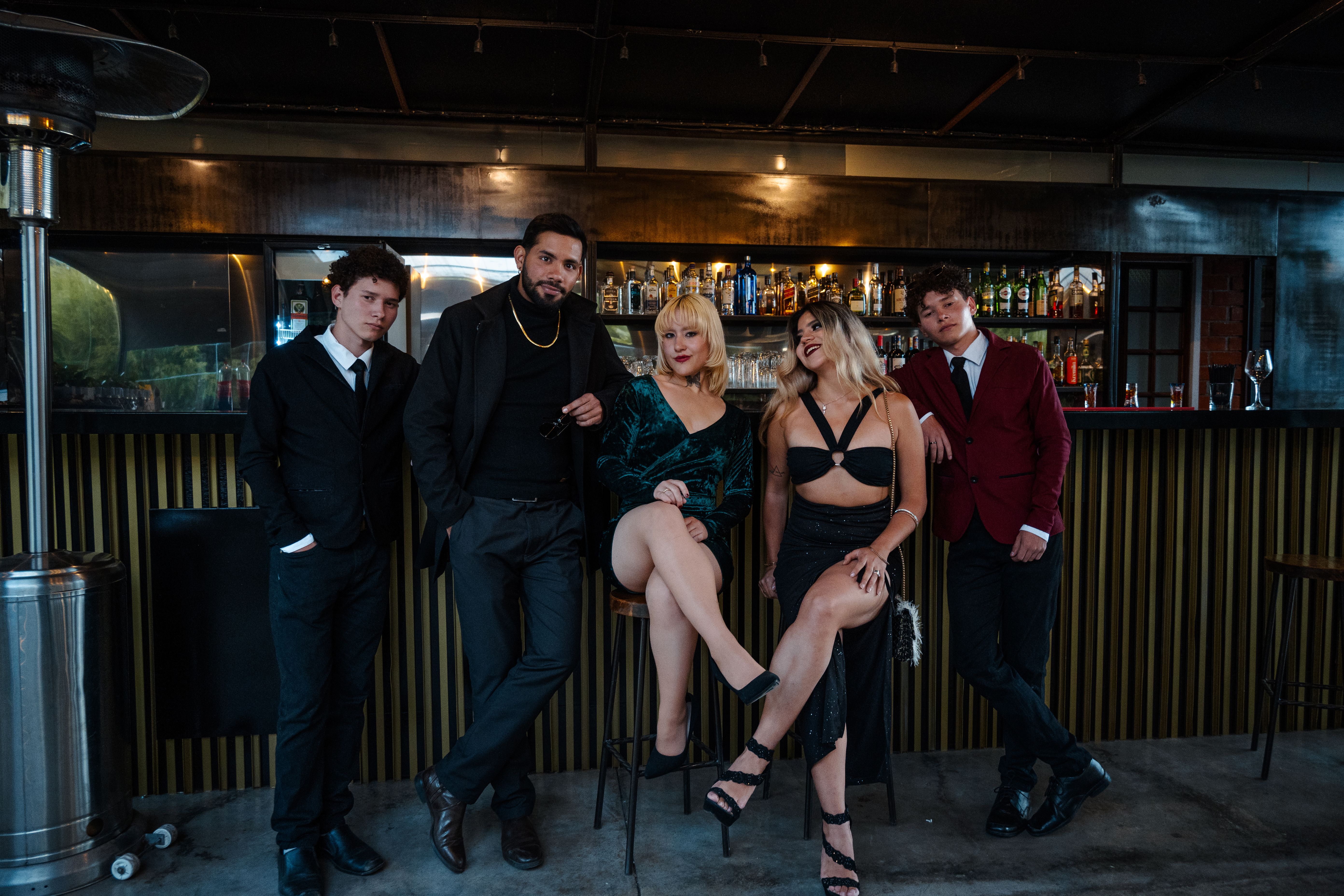 Elegant group of adults posing fashionably inside a bar with a sophisticated ambiance.