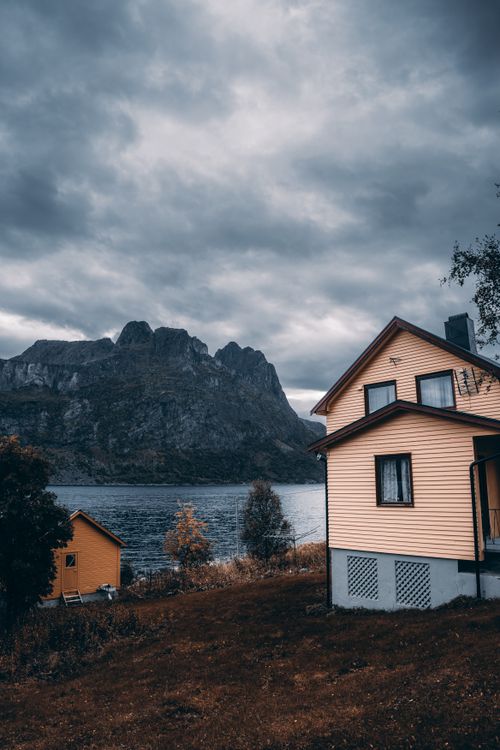 Free Yellow cabin by a tranquil lake with stunning mountain views in Tromsø, Norway. Stock Photo