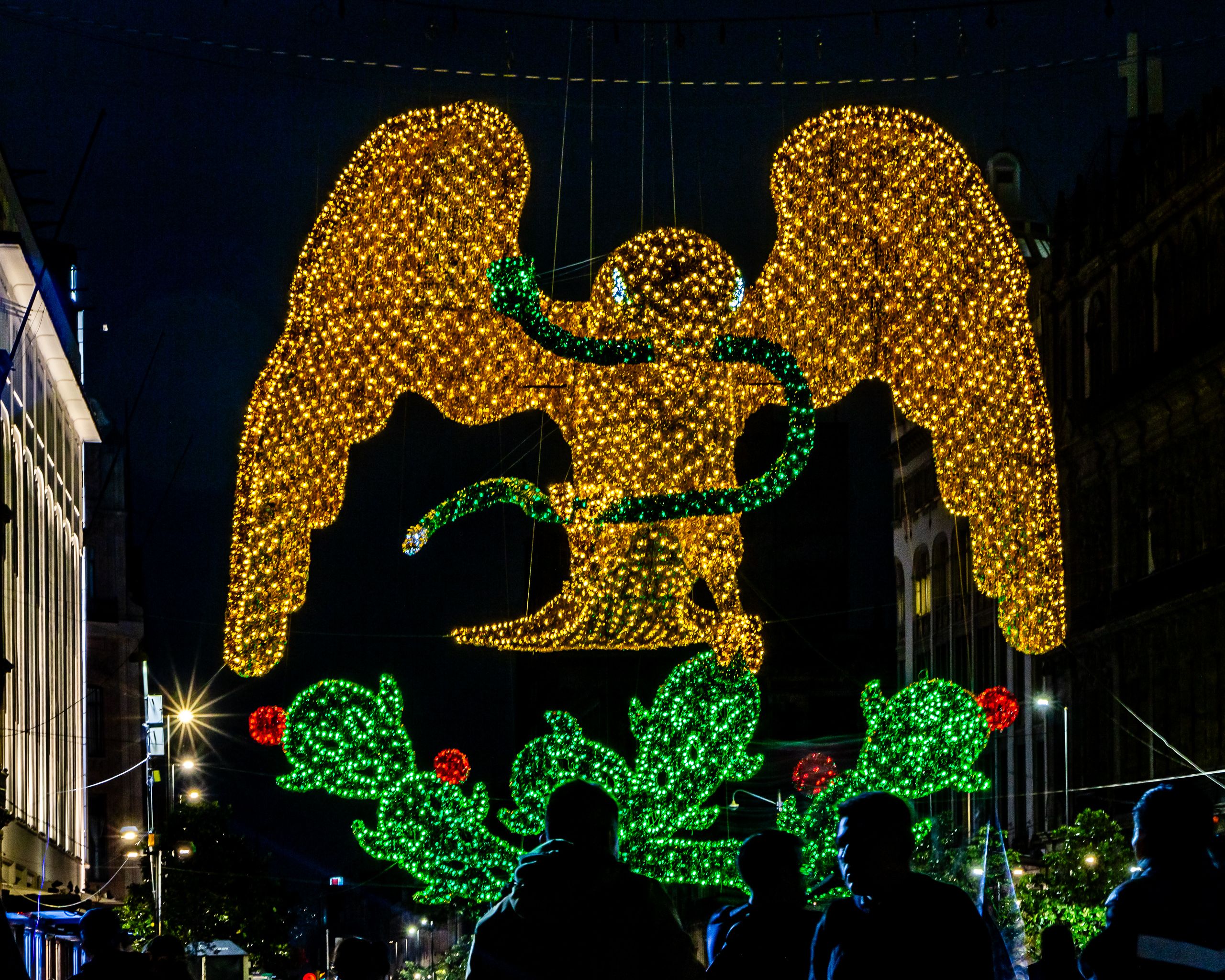 Vibrant night scene featuring an illuminated eagle with a serpent, capturing festive lights in Ciudad de México.