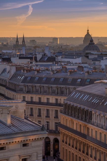 Stunning aerial view of historic Paris rooftops under a warm sunset sky.