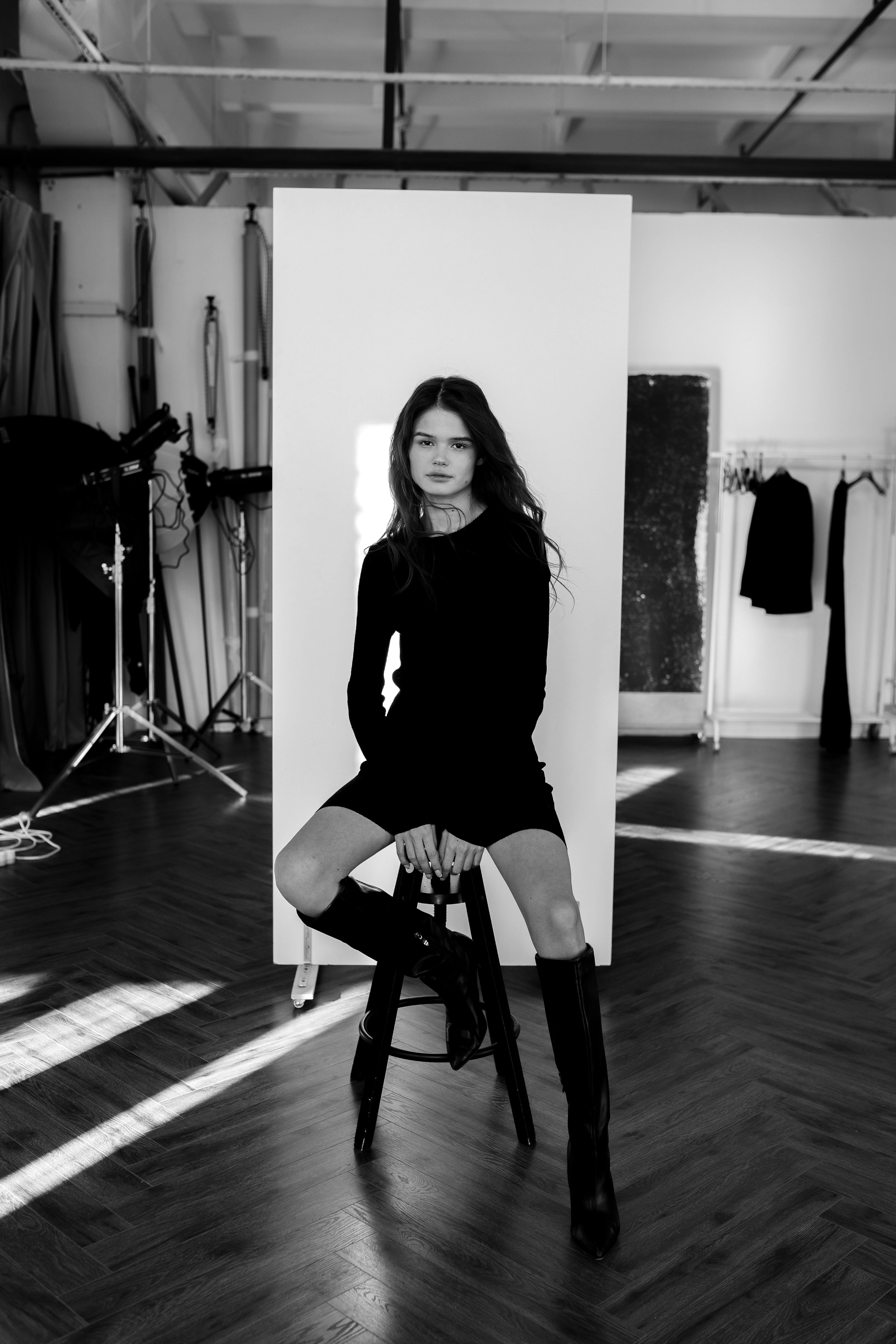 Artistic black and white portrait of a woman seated in a modern studio.