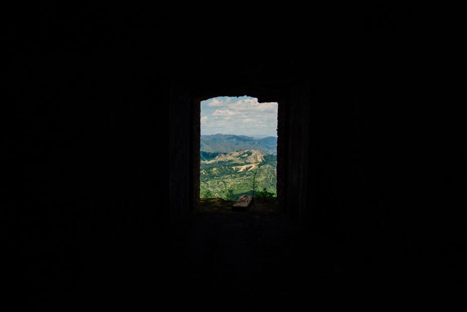 A picturesque view of mountains framed by a dark window, creating a dramatic contrast.