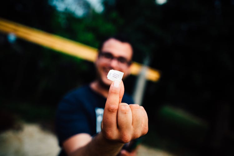 Selective Focus Photo Of Man In Black T-shirt Hand Glasses Holding Out Piece Of Paper