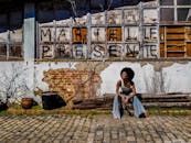 一位非裔巴西妇女在一堵带有“玛丽埃尔·普森特”涂鸦的乡村城墙前微笑