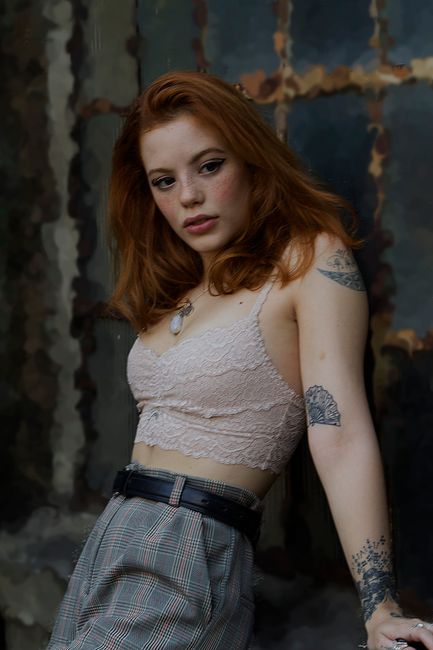 Elegant portrait of a tattooed woman in fashionable attire against a textured background.