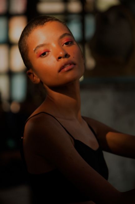 Striking portrait of a woman with red eye makeup in warm, soft lighting indoors.