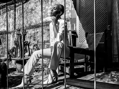 Woman Sitting on Chair Beside Metal Bars