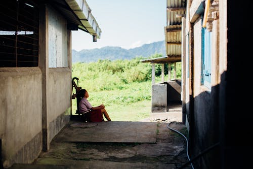 Woman Sitting Beside Hand Water Pump