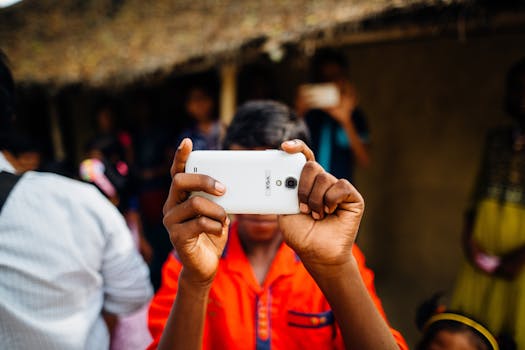 在拥挤的户外环境中，一个穿着鲜艳衣服的人正用智能手机自拍