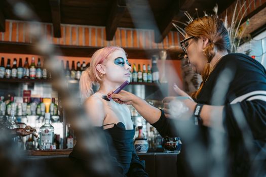 Makeup artist working on model inside a vibrant Mexican bar.