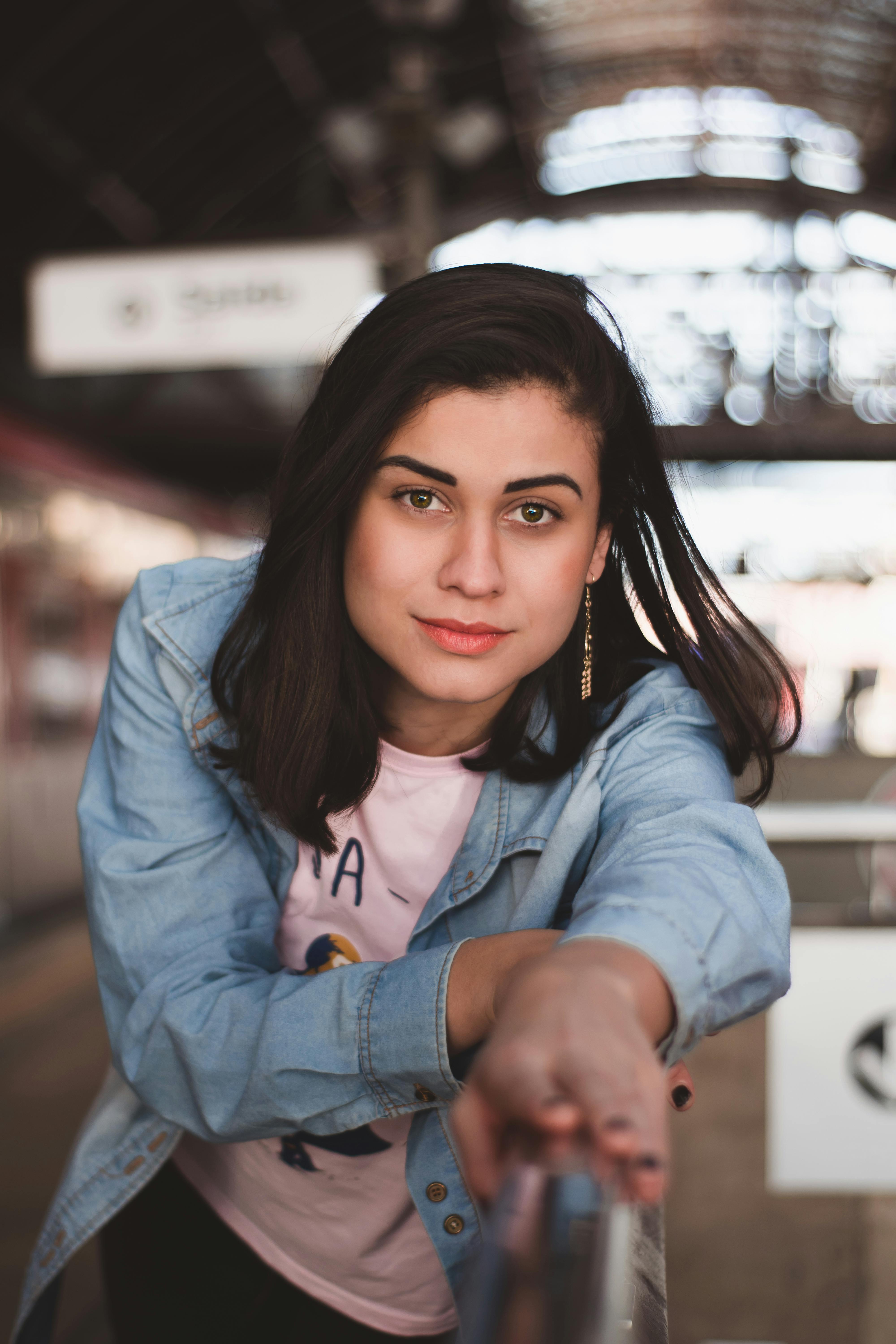 一位身穿牛仔夹克的女性自信地站在火车站，展现出现代时尚风格