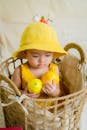 可爱的幼儿戴着黄色帽子，拿着柠檬坐在柳条篮子里