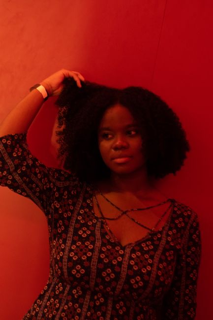 Stylish portrait of a woman with curly hair against a moody red backdrop.