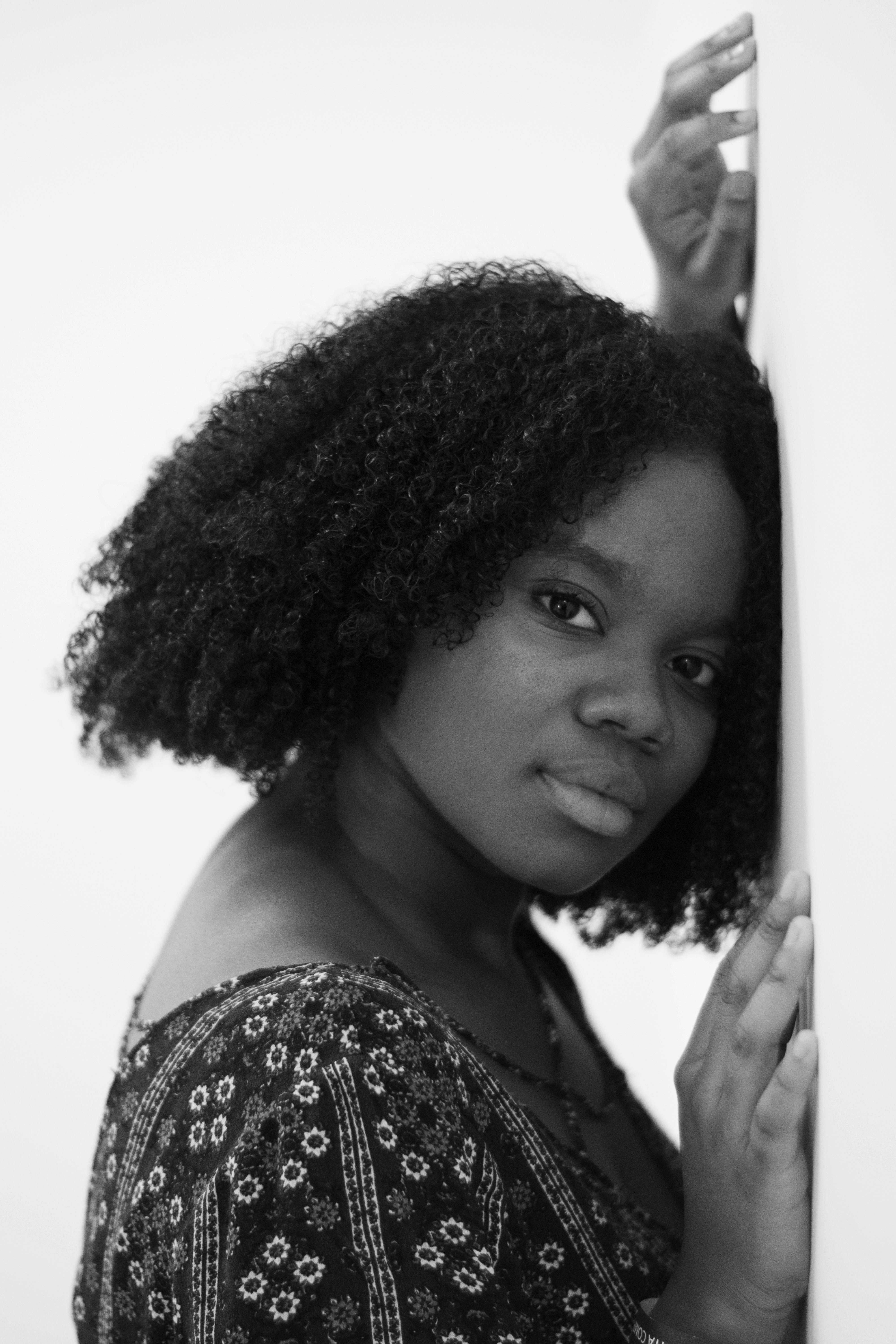 黑白肖像画中，一位年轻女子倚墙而立，神情平静而沉思