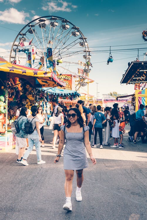 Mulher De Minivestido Cinza De Gola Quadrada E Tênis Branco Andando Na Rua Com Fundo De Roda Gigante