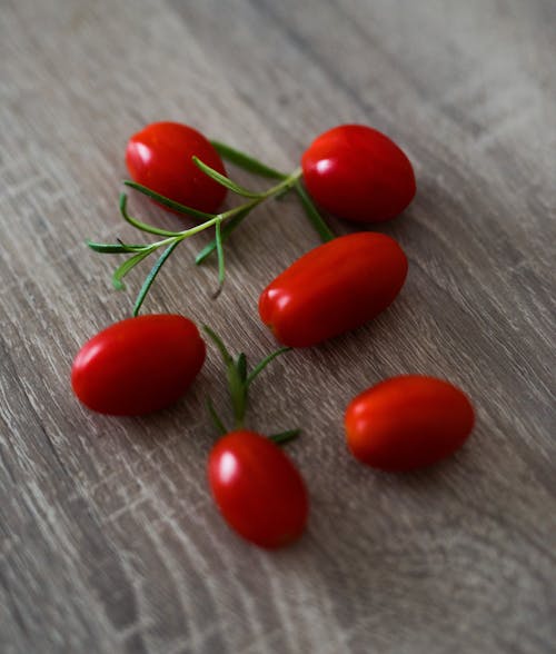 Six Red Goji Berries on Brown Wooden Surface