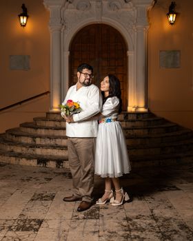 A couple poses romantically in traditional attire during their engagement at night in Mérida, México.