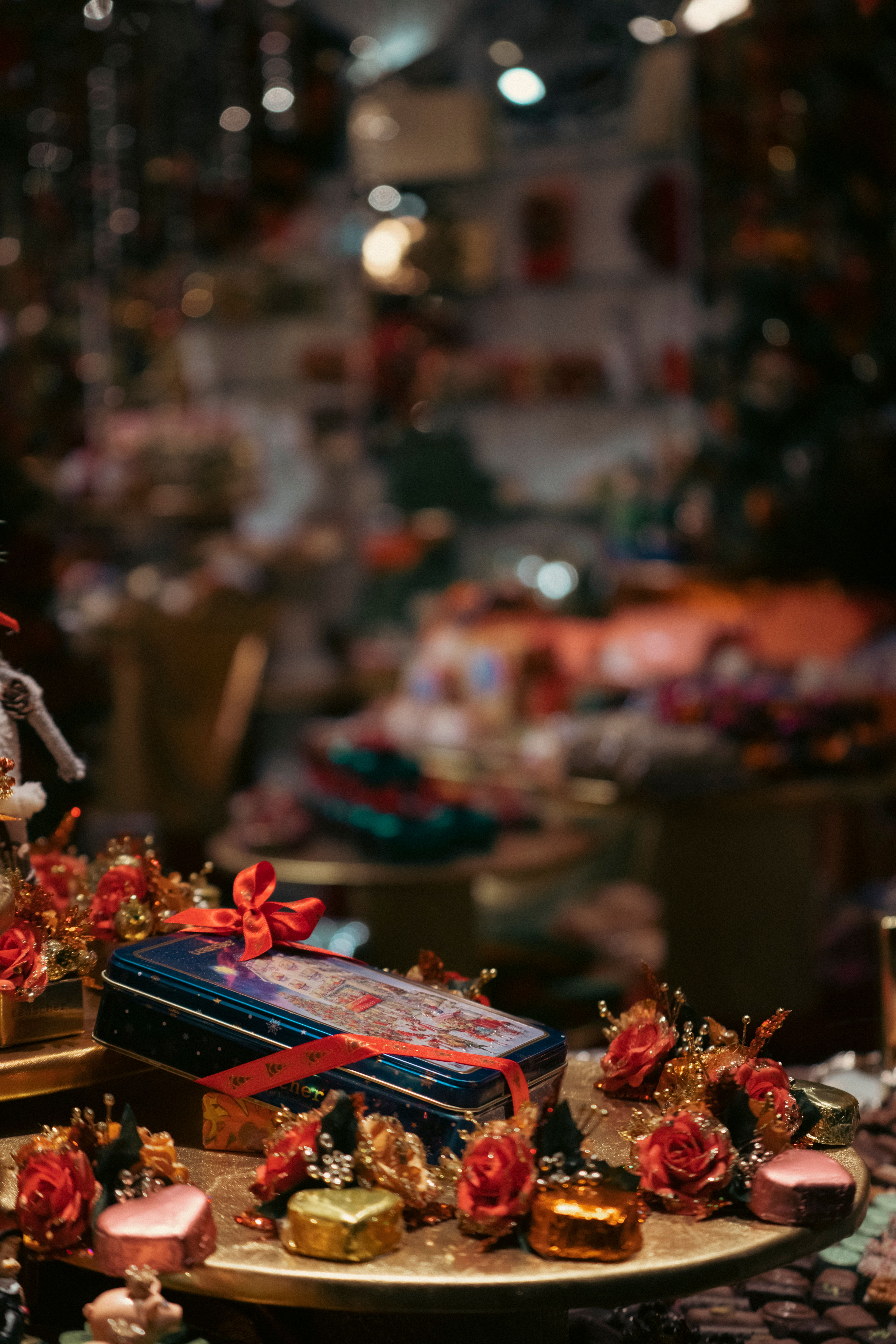A festive table display featuring wrapped gifts, red roses, and holiday decor under warm lighting.