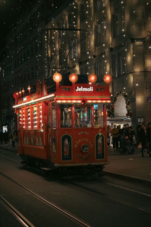 Free A bright red tram illuminated on a festive street, capturing the spirit of winter holidays. Stock Photo