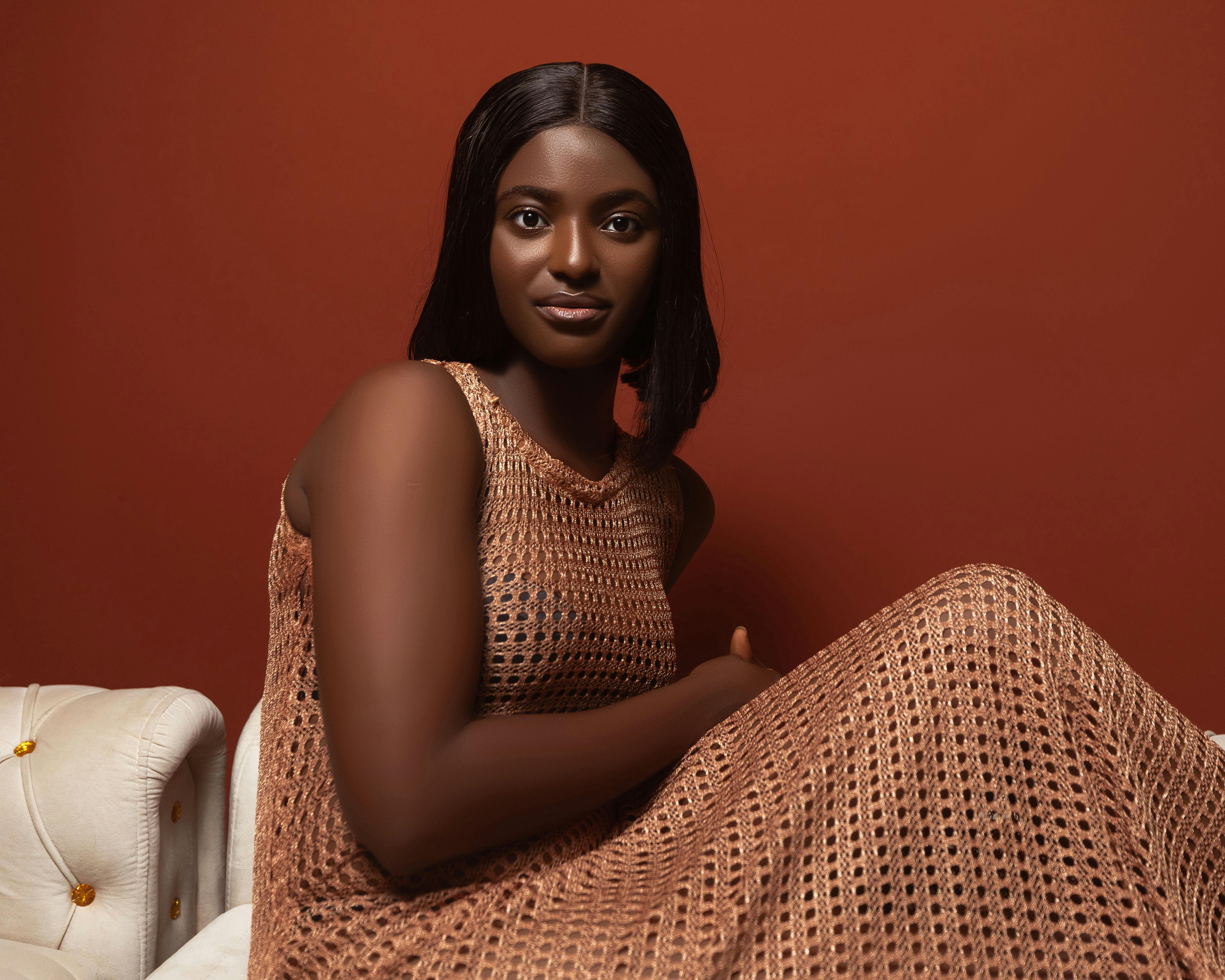 Portrait of a woman in a warm hued knit dress against a matching backdrop.