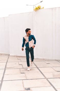 一位衣着随意的男子在户外摆姿势，展示着时尚服装和太阳镜