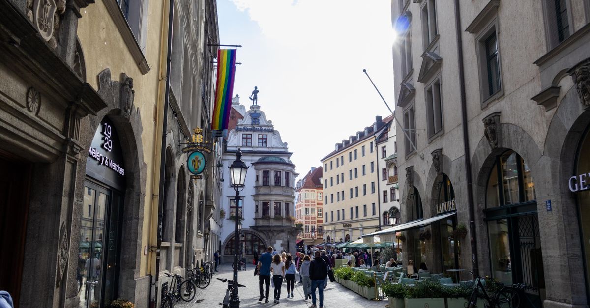 Rainbow flags lining a European city street with outdoor cafes