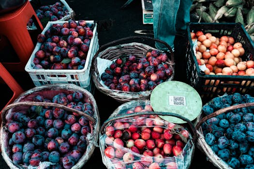 Baskets filled with fresh plums and apricots at a vibrant outdoor market stall.