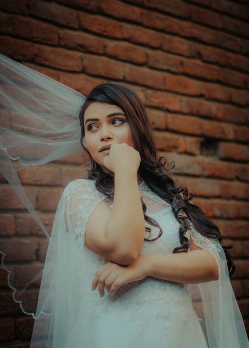 Free Stunning portrait of an Indian bride in traditional attire posing by a rustic brick wall. Stock Photo