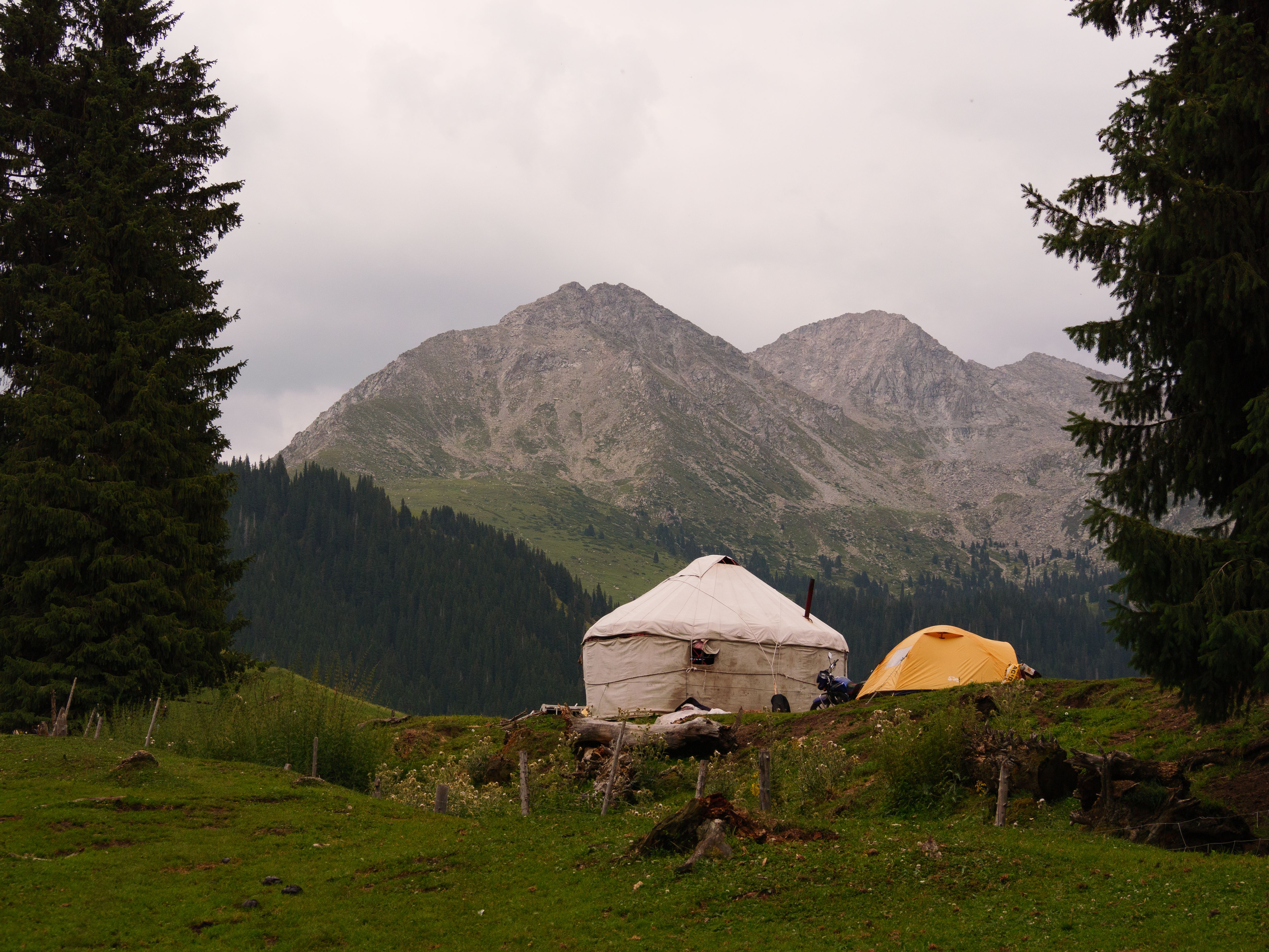 A picturesque landscape featuring a yurt and tent against a mountain backdrop.