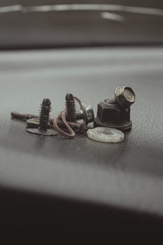 Detailed close-up of various metal screws and bolts on a textured surface, ideal for industrial themes.