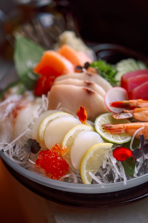 Free A vibrant close-up of a freshly prepared sashimi platter featuring fish, shrimp, and citrus garnishes. Stock Photo