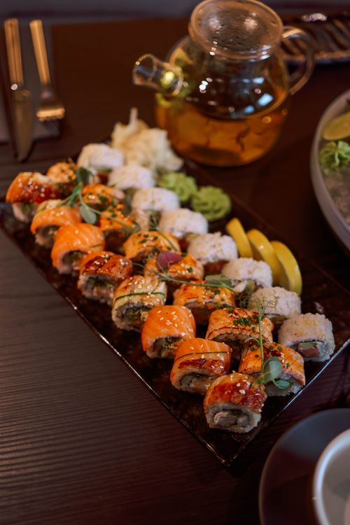 Free Colorful sushi platter with assorted rolls and tea pot for an elegant food presentation. Stock Photo