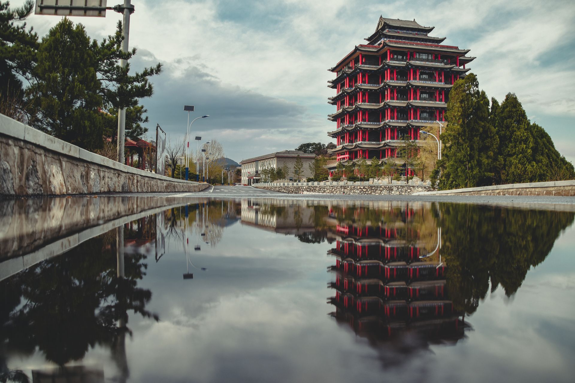 Stunning view of a traditional pagoda in Taiyuán, reflecting in a puddle on a cloudy day.