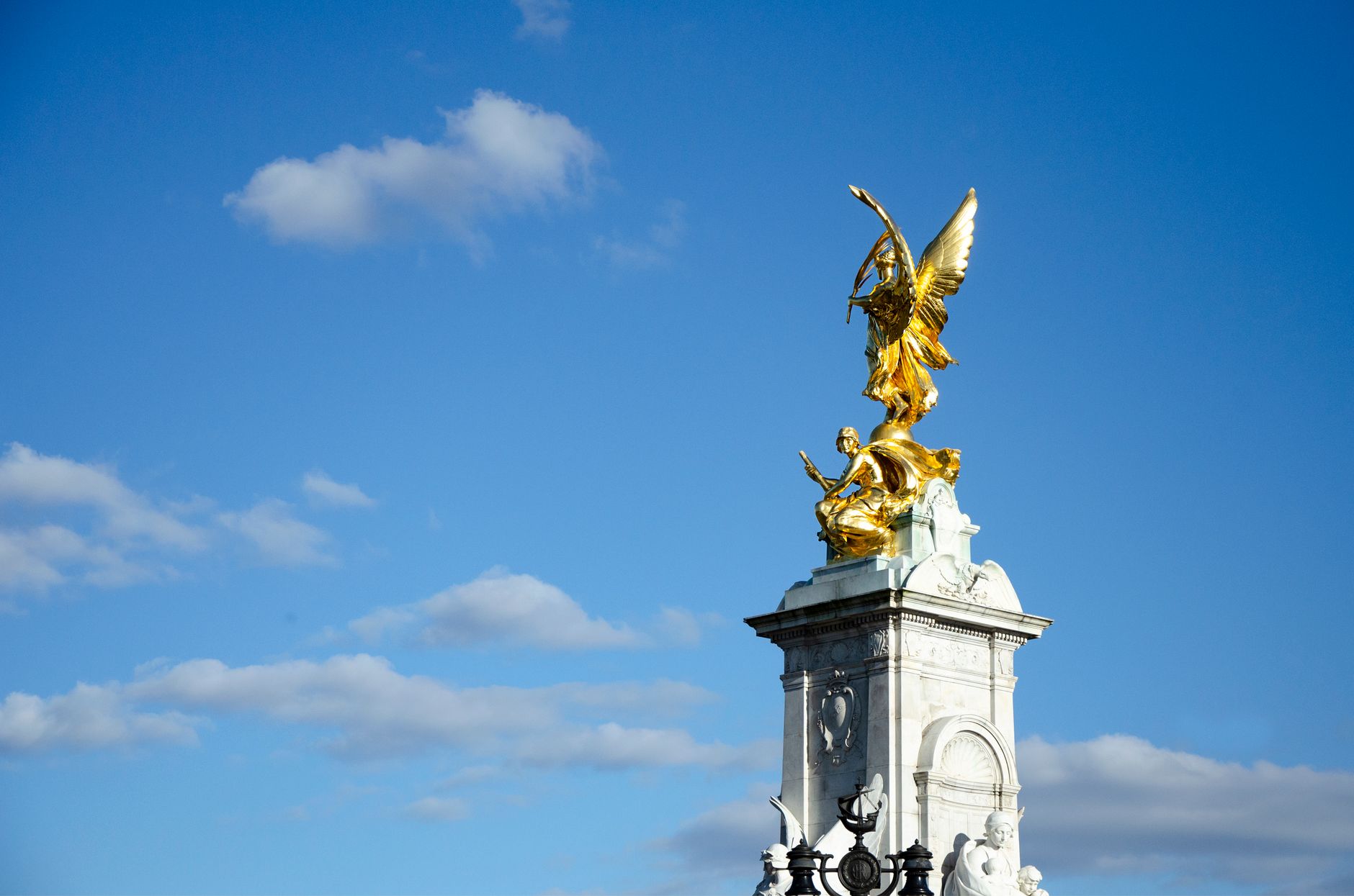 Golden statue of Victoria Memorial, London set against a clear blue sky.