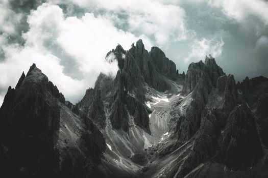 Stunning view of rugged mountain peaks shrouded in clouds, conveying a dramatic and moody atmosphere.