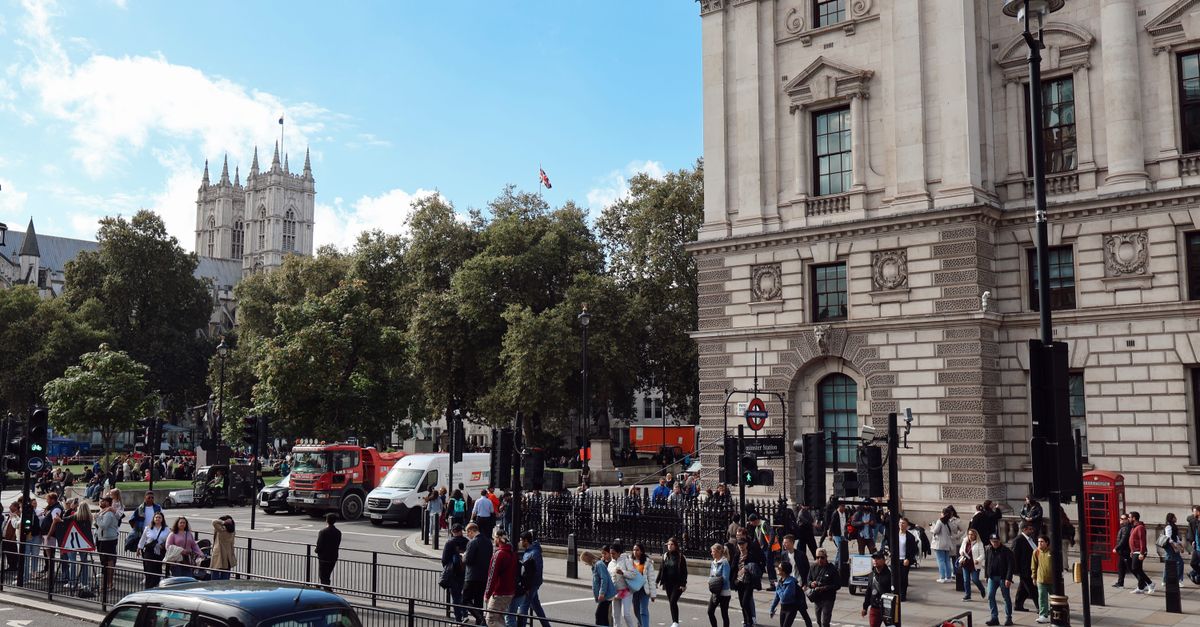 Vibrant scene of a busy London street with a view of Westminster Abbey and iconic red telephone booth.