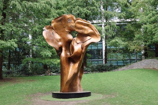 Bronze sculpture in lush green Jubilee Park, London, surrounded by trees.
