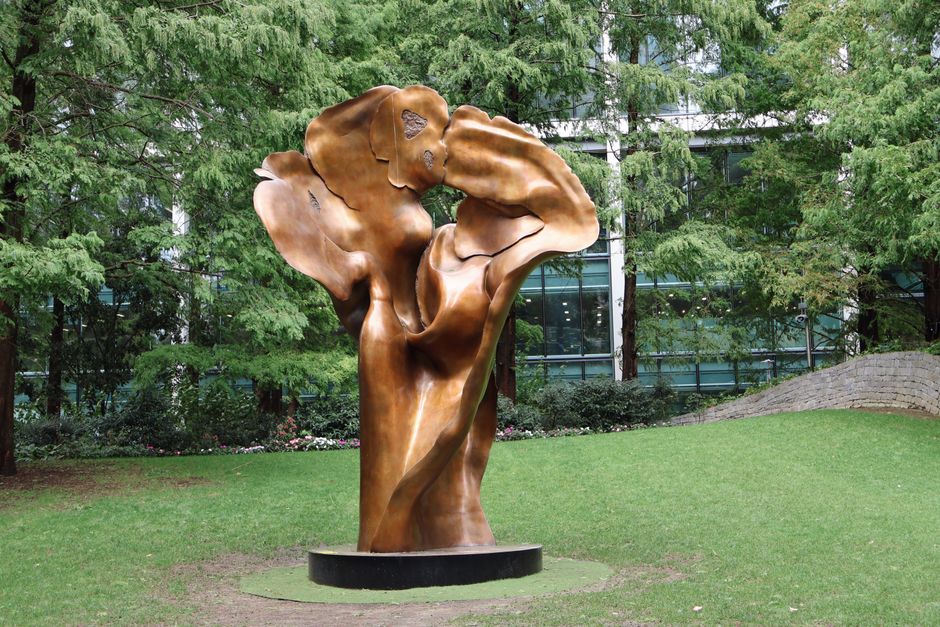 Bronze sculpture in lush green Jubilee Park, London, surrounded by trees.