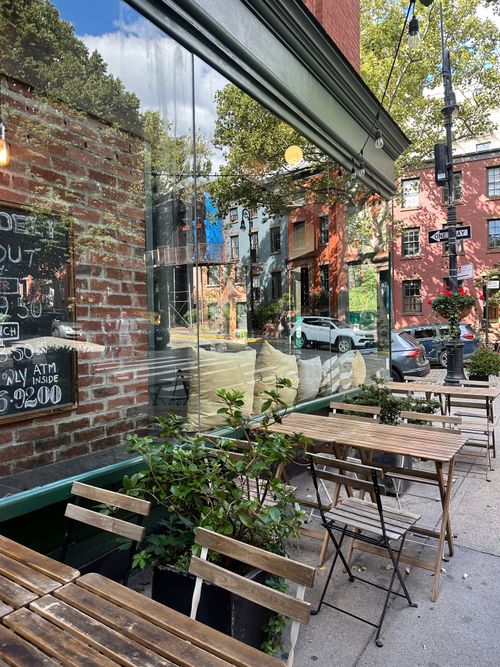 Free Inviting sidewalk cafe in New York City with outdoor seating and urban reflections. Stock Photo