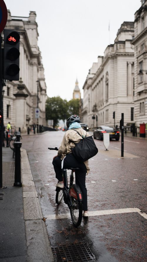 Free A cyclist rides a bike on a rainy street in London, with Big Ben visible in the background. Stock Photo