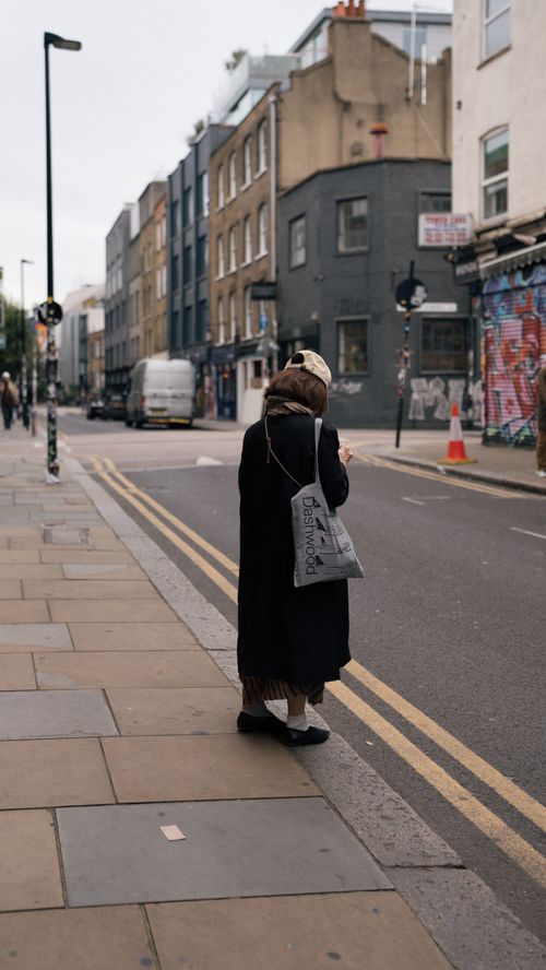Free Woman standing on urban street corner, capturing vibrant city life. Stock Photo